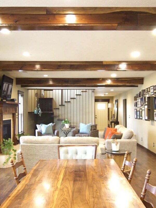 open concept dining room and living room with wood beams and floating staircase