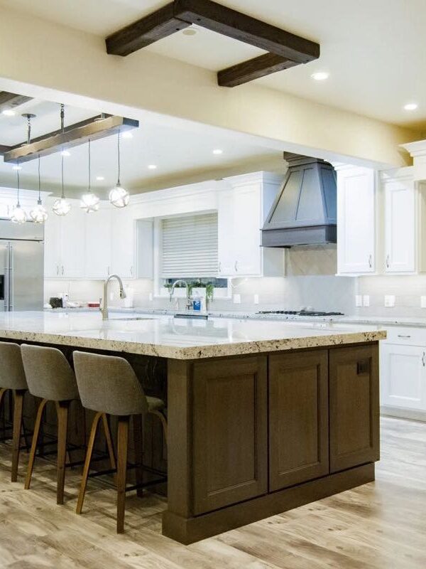 large kitchen with massive 7 seater island, white cabinets, and wood accents