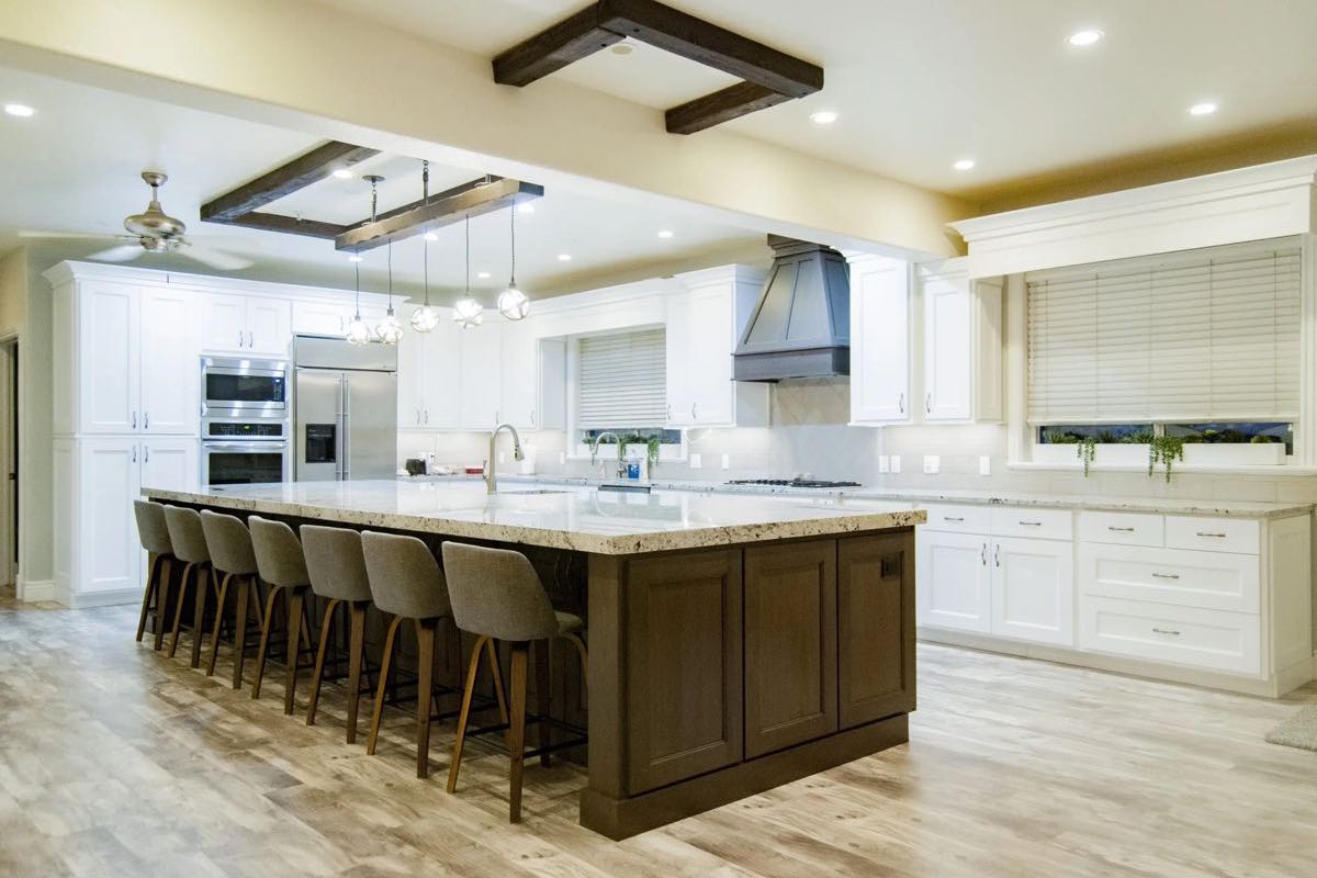 large kitchen with massive 7 seater island, white cabinets, and wood accents