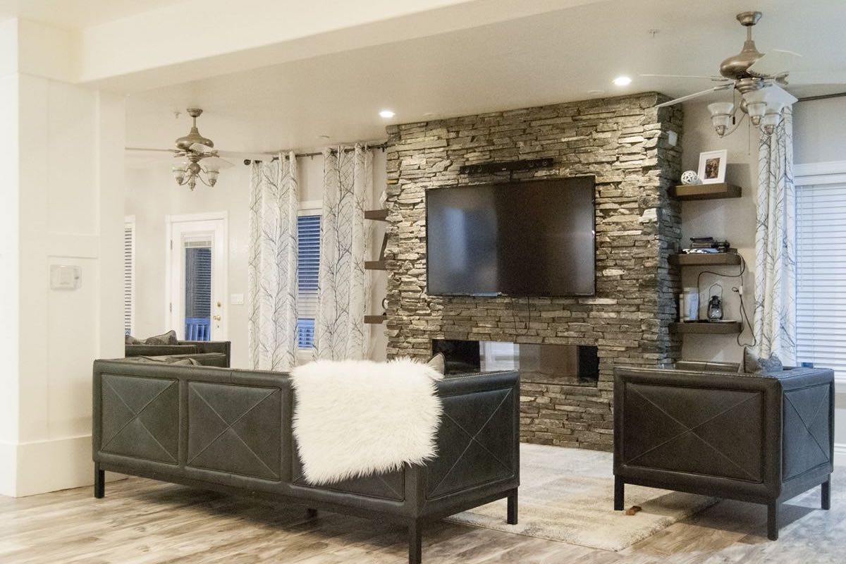 living room with stone fireplace and wall mounted tv