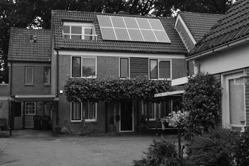 A home with solar panels on its roof. Black and white photo.