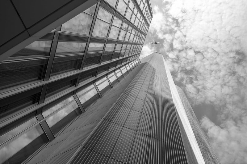 Black and white photo of a skyscraper looking up at street level.