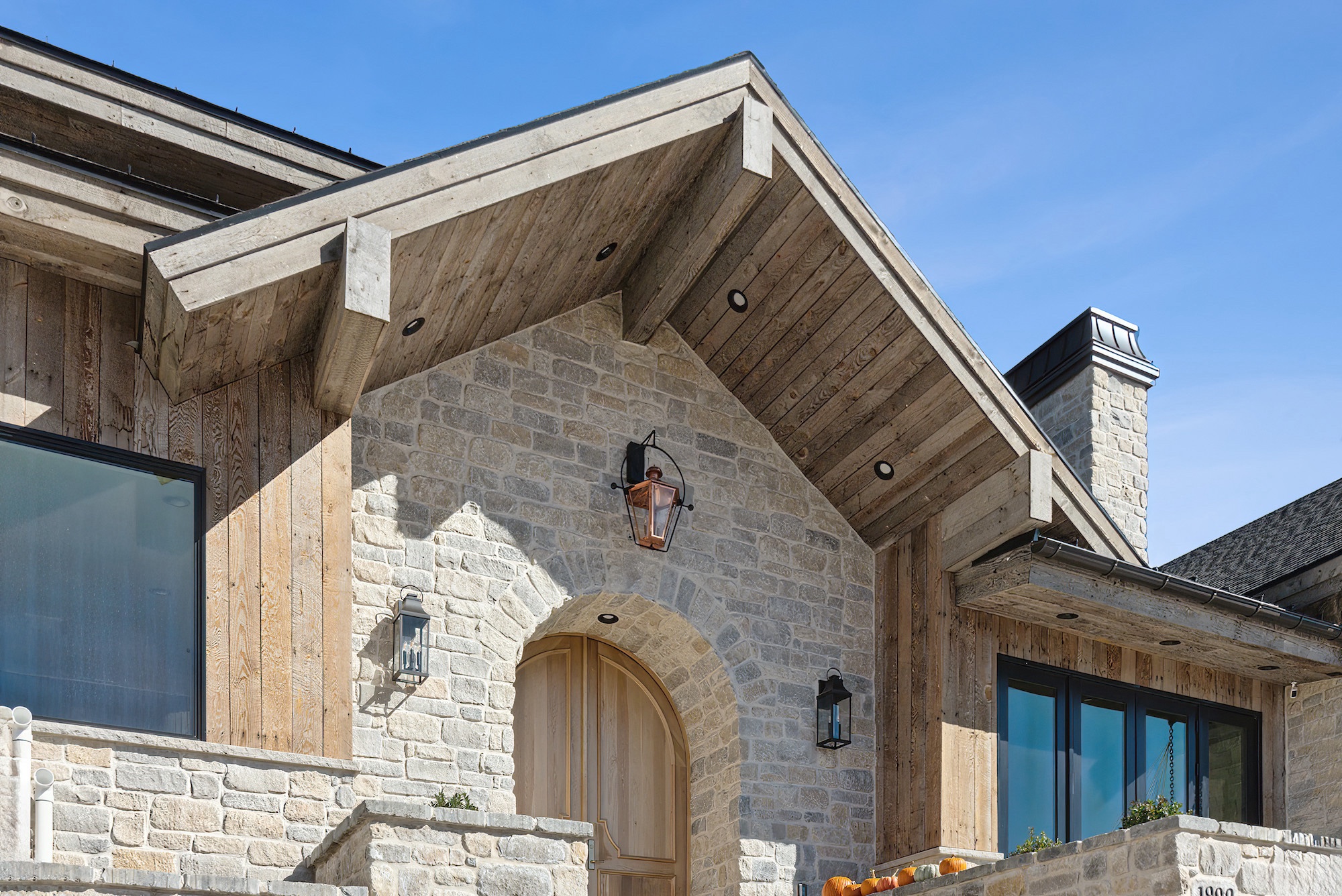 Exterior detail photograph of a custom home entry with stone, wood, and arched door in Golden Eagle, Hideout, Utah.